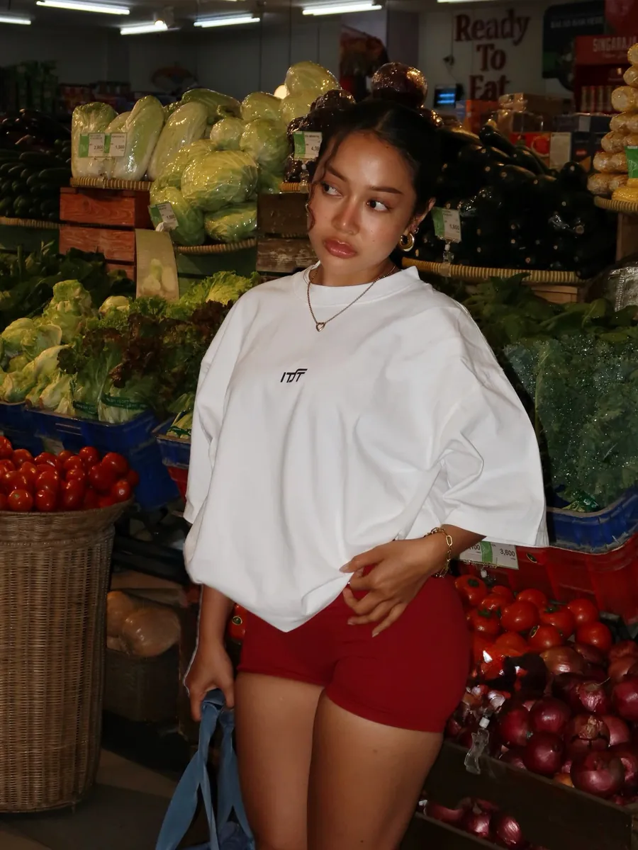 Jean in an oversized white tee at a fruit and vegetable market